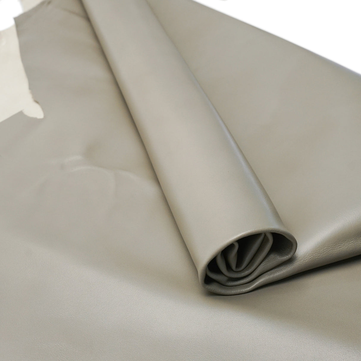 A roll of light gray leather, shown partially unrolled to display its smooth texture and matte finish.