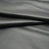 A close-up of dark gray pebbled leather 
with soft folds and a smooth texture.