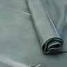 A close-up of a rolled piece of smooth leather in a muted sage green color, laid out on a matching background.
