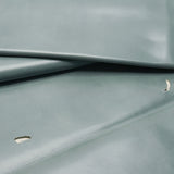 A close-up of a smooth, slightly glossy fabric or material in a muted blue-gray color, folded to show texture and drape.