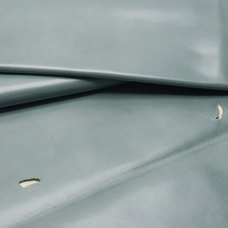 A close-up of a smooth, slightly glossy fabric or material in a muted blue-gray color, folded to show texture and drape.