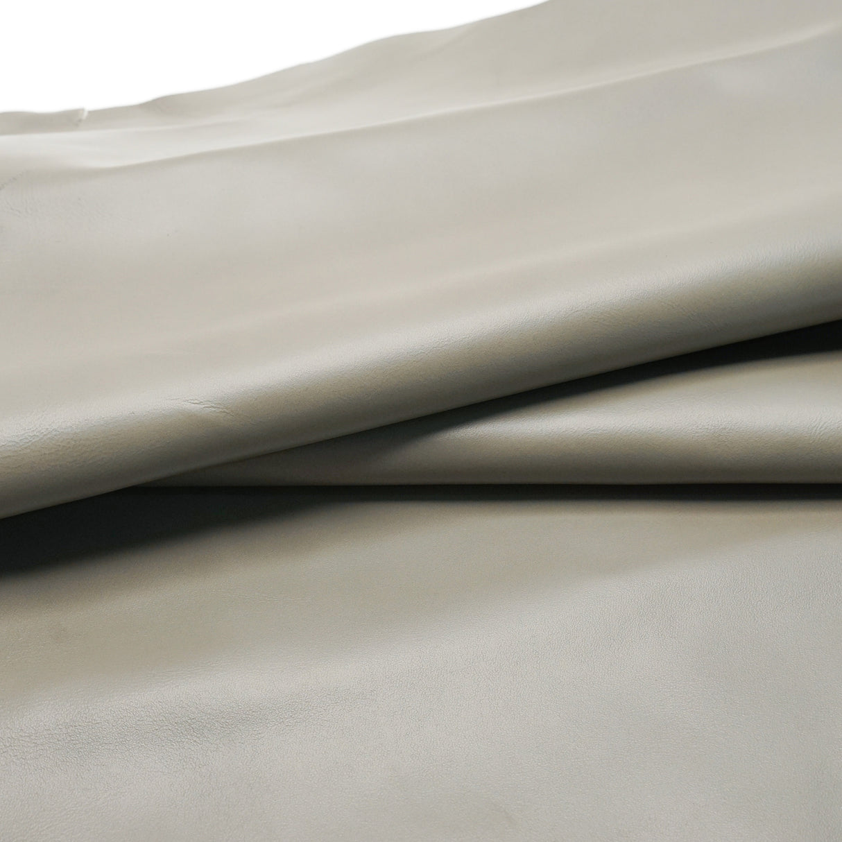 A close-up of draped light beige leather  with a smooth texture and soft shadows.