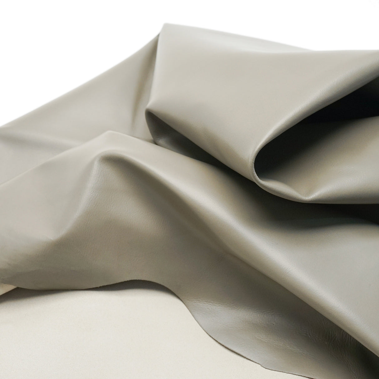 A draped piece of smooth, light gray fabric with soft folds and shadows, set against a clean white background.