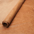 A roll of textured tan leather placed diagonally on a matching flat sheet of the same material.