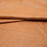 A close-up of draped tan leather with a soft, slightly textured surface.