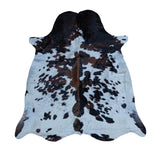 A natural cowhide rug with a black and brown spotted pattern on a white base, displayed flat against a solid white background.