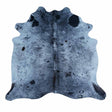 A natural cowhide rug with a blue-gray base and black spots, shown flat against a white background.